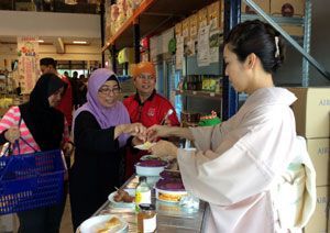 ハラル認証を得た県産食品を試食する現地の人（左）＝シンガポールの専門店（県提供）