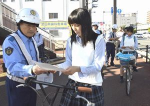 自転車の高校生らにチラシを配り講習制度を説明する東署員＝徳島市の徳島本町交差点