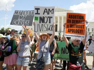 　２５日、ワシントンの米連邦最高裁前で「私の体、私の選択」などのスローガンを掲げて中絶の権利を認めない判断に抗議する女性たち（共同）