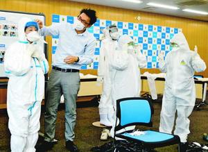 PCR検査外来の開設を控え、防護服の着脱訓練をする参加者=徳島市の県医師会館