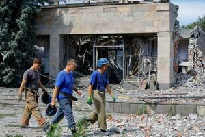 　８日、ウクライナ東部ドネツク州で、攻撃を受けたホテルの前を歩く救助隊員（ロイター＝共同）