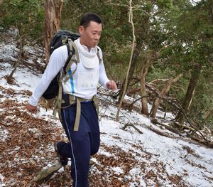 雪の積もった山道を重りを背負って走る参加者＝那賀町沢谷