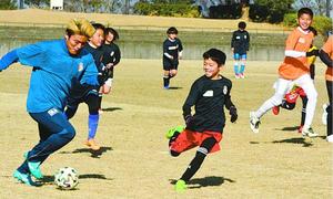 表原選手(左端)らとサッカーを楽しむ子どもたち=徳島市球技場