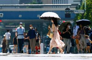 　猛烈な暑さの中、銀座を行き交う人たち。東京都心では３５・４度を観測して今年初めて猛暑日となった＝２５日午後