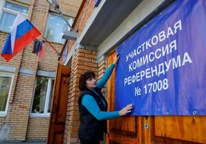 　２２日、ウクライナ東部ドネツク州の「住民投票」投票所で横断幕を掲げる地元の「選挙管理委員会」関係者（ロイター＝共同）