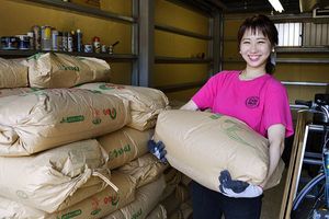 30キロの米袋を持ち上げる悠衣さん=徳島市中徳島町2の「しのみや商店」
