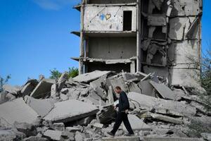　２５日、ウクライナ・ドネツク州で破壊された家屋の横を歩く地元住民（ＡＰ＝共同）