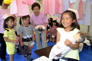 助産師体験コーナーで赤ちゃんの人形を抱く子ども＝石井町のＯＫいしいパーク