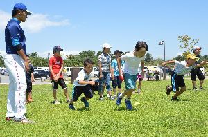 徳島インディゴソックスの選手（左端）の指導の下、ダッシュをする小学生＝松茂町の月見ケ丘海浜公園