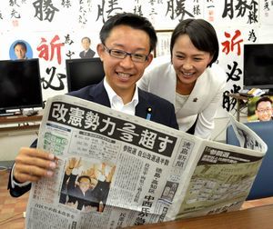 妻の紗希さんと共に当選を伝える新聞に目を通す中西さん＝高知市の事務所