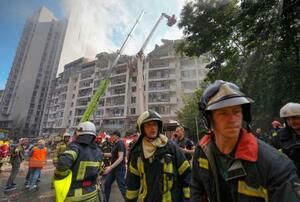 　ウクライナの首都キーウでミサイル攻撃を受けた集合住宅。煙が上がる中、消火活動が行われていた＝２６日（共同）