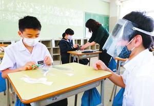 教員(右)にフェースシールドの作り方を教わる生徒=徳島市の津田中