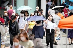 　猛烈な暑さの中、ＪＲ浦和駅前を行き交う人たち＝２６日午前、さいたま市