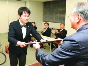 米田代表理事から贈呈書と支援金を受け取る榮社長(左)=徳島市の徳島新聞社