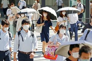 　厳しい暑さの中、日傘を差して歩く人たち＝２７日午前、ＪＲ東京駅前