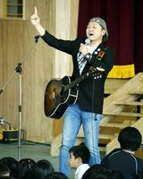 歌を交えて講演する松本さん＝美馬市美馬町の美馬小学校
