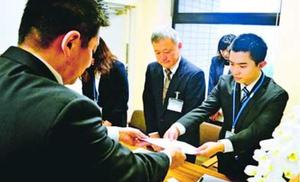 職員にパートナーシップ宣誓書を渡す長坂さん(手前)=徳島市役所