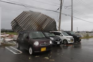 空き店舗の一部が屋根ごと飛ばされ、近くの車を壊した＝４日午後、阿南市日開野町