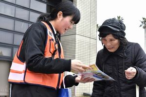 特殊詐欺への注意を呼び掛けるチラシを手渡す警察官（左）＝徳島市役所
