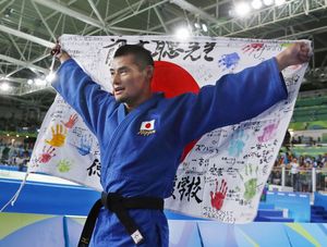 銅メダルを獲得し、徳島視覚支援学校の関係者が寄せ書きをした日の丸を掲げる藤本選手＝リオデジャネイロ