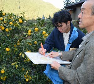ユズ畑の位置を確認し地図に書き込む学生（左）と古田教授＝那賀町木頭南宇