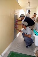 トイレの壁を修繕する「子供の環境を支援する会・羽ノ浦」の会員＝羽ノ浦小