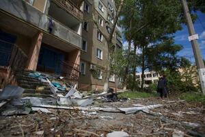 　ロシア軍の攻撃で損傷した建物近くに立つ女性＝２２日、ウクライナ・ドネツク州（ロイター＝共同）