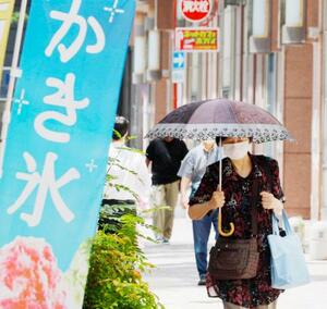 　日傘をさして福岡・天神を歩く人。気象庁が九州北部、四国などで梅雨明けしたとみられると発表した＝２８日午後