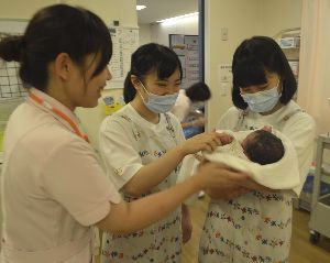 生まれて間もない赤ちゃんを抱く生徒（右の２人）＝小松島市の徳島赤十字病院