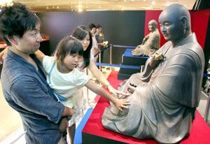 複製された弘法大師坐像に触れる親子連れ＝そごう徳島店