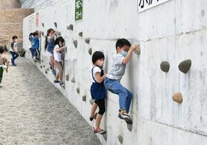 　オープンした、砂防ダムを活用した施設でボルダリングに挑戦する子どもたち＝２１日午前、秋田県仙北市