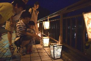 夏らしいイラストで美しく彩った七夕あんどんを見詰める家族連れ＝牟岐町中村の大川橋