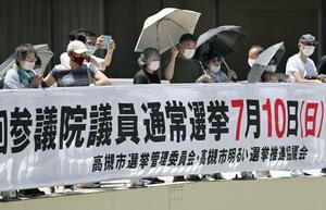 　強い日差しの中、日傘にマスク姿で街頭演説を聞く有権者ら＝２９日午前、大阪府高槻市（画像の一部を加工しています）