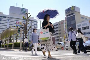 汗ばむ陽気の中、日傘を差して歩く女性＝９日午後2時ごろ、徳島市の徳島駅前