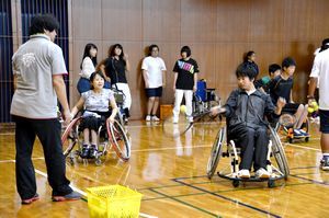 岡部さん（左から２人目）に教わりながら、車いすテニスを体験する参加者＝徳島市の県立障がい者交流プラザ