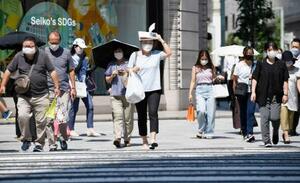 　強い日差しの中、マスク姿で横断歩道を渡る人たち＝９日午後、東京都中央区