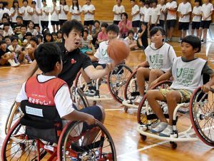 根木さん（中央）と車いすバスケットボールを体験する高川原小児童＝同校