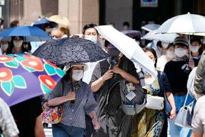 　猛烈な暑さの中、日傘を差して歩く人たち＝２６日午後、東京・銀座