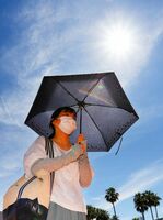 短い梅雨が明け、強い日差しを日傘でよける通行人=28日午前10時ごろ、徳島駅前