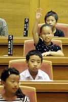 子ども県議会で質問するため挙手をする小学生＝県議会議場