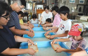 木枠を使って和紙の原料の繊維をすくう参加者＝吉野川市の阿波和紙伝統産業会館