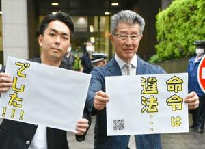 　判決後、東京地裁前でボードを掲げるグローバルダイニングの長谷川耕造社長（右）ら＝１６日午後、東京・霞が関