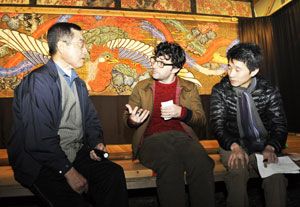 小川会長（左）から襖からくりについて話を聞くドーンさん（中）＝神山町神領の小野さくら野舞台