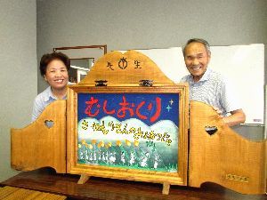 虫送りの伝承を説明する紙芝居を作った田村館長（左）ら＝阿南市の長生公民館