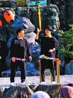 地面に突き刺した傘が跳ね返ってくる芸を披露するゼロコの2人=小松島市小松島町の小松島ステーションパーク