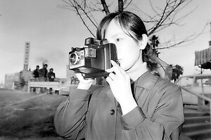 インスタントカメラを構える女性。現像が不要とあって人気を集めた=1972(昭和47)年、徳島市内(本社所蔵写真)