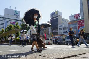 強い日差しの中、日傘を手に歩く人たち＝午後3時ごろ、徳島駅前