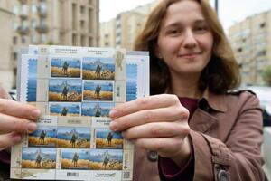 　限定発売された記念切手を持つ女性＝２３日、ウクライナ・キーウ（共同）