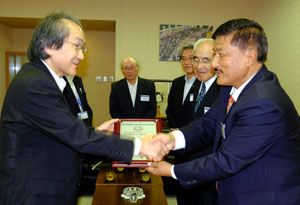 植田社長（左）に盾を手渡し、握手を交わすビシュヌ会長＝徳島市の徳島新聞社