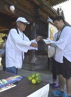 スダチを配り、お遍路さんをもてなす四国遍路同行会の木村さん（左）＝小松島市立江町の立江寺